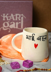 White mug with text, marigold flowers, and decorative items on a marble surface with 'Kari Garl' box in the background.